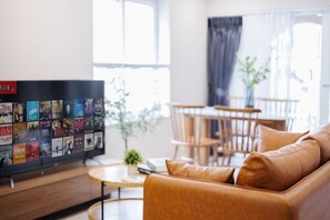 A living room with a leather sofa, a coffee table, and a TV displaying a selection of movies. - VietHOME - 22 Pho Hue - Apartment 502 (Hanoi)