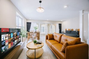 Una sala moderna con un sofá de cuero, una mesa de centro y un televisor que muestra la interfaz de Netflix.