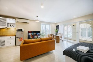 Una habitación de hotel moderna con sofá, cama, zona de comedor y cocina.