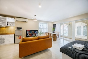 Una habitación de hotel moderna con sofá, cama, zona de comedor y cocina.
