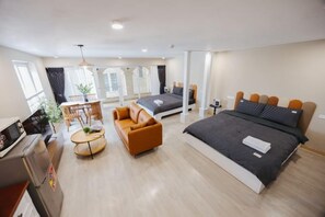 A modern hotel room with a large bed, a sofa, a dining table, and a kitchenette. - VietHOME - 22 Pho Hue - Apartment 502 (Hanoi)
