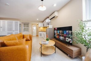 A modern living room with a sofa, a coffee table, and a flat-screen TV. - VietHOME - 22 Pho Hue - Apartment 502 (Hanoi)