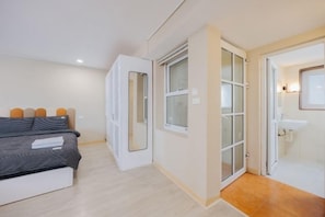 Un dormitorio con cama, ventana y baño con lavamanos.
