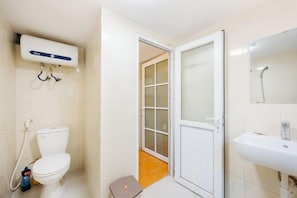 A bathroom with a toilet, a sink, and a shower area. - VietHOME - 22 Pho Hue - Apartment 502 (Hanoi)