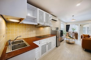 A modern kitchen with white cabinets, a stainless steel sink, and a wooden countertop. - VietHOME - 22 Pho Hue - Apartment 502 (Hanoi)