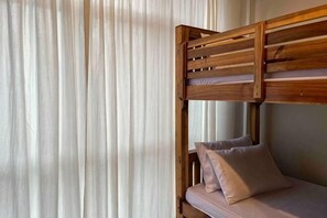 Una cama litera con estructura de madera y un colchón con almohadas.