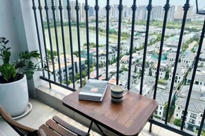 Een balkon met een tafel, een bloempot en uitzicht op een stadsgezicht.