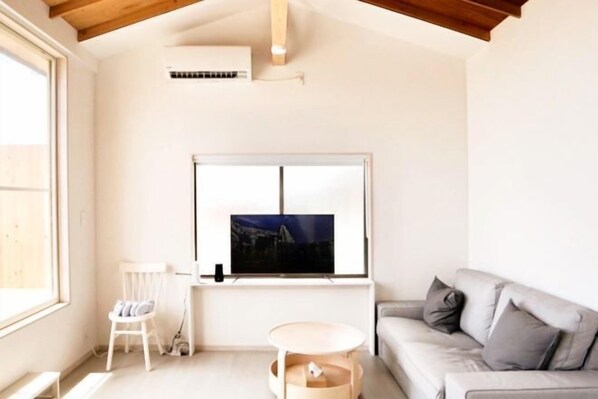 A living room with a television, a sofa, a chair, and a small round table. - and SEA The Terrace (Kamogawa)