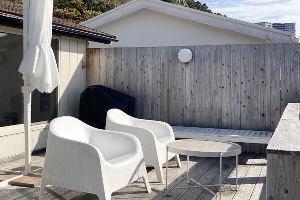 A patio area with white plastic chairs, a round table, and a barbecue grill. - and SEA The Terrace (Kamogawa)
