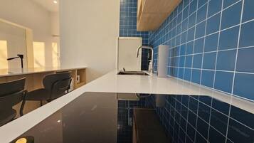 Een moderne keuken met een zwart aanrecht, witte kasten en een blauwe tegelachtergrond.
