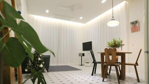Una habitación con una mesa de comedor, sillas, un televisor y una planta.
