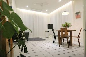 Una habitación con una mesa de comedor, sillas, un televisor y una planta.