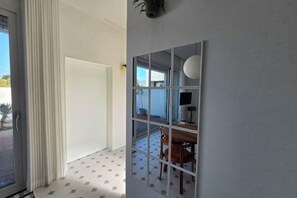 A room with a sliding glass door, a tiled floor, a white wall with a decorative panel, and a view of an outdoor area with a table and chairs. - Yuyuhi Private Pool Villa (Jeju)