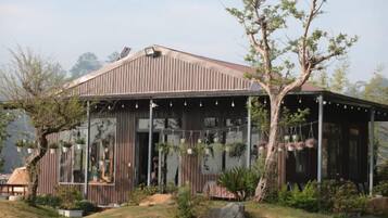 A modern building with a sloped roof, large windows, and a covered outdoor area.