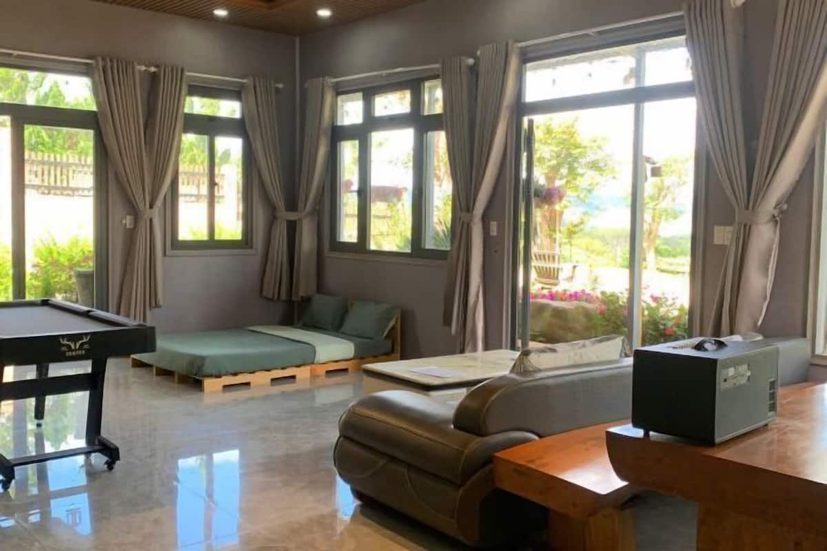 A modern room with a pool table, a sofa, a bed, and a desk with a computer.
