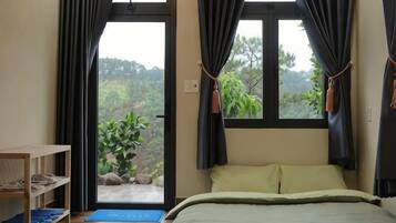 A bedroom with a bed, a desk, and a view through a door.
