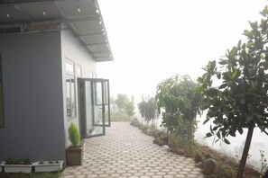 A pathway leading to a building with a modern design, surrounded by greenery and a foggy atmosphere. - Mountain Nest Villa Dalat - BBQ, Cloud Hunting, Camping (Lac Duong District)