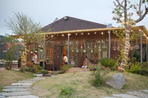 Una casa de madera con un porche cubierto, un camino de piedra y plantas colgantes.