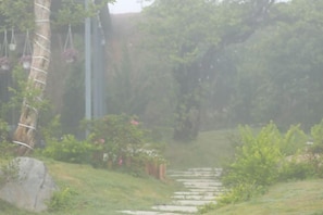 A stone pathway leading through a garden with greenery and hanging plants. - Mountain Nest Villa Dalat - BBQ, Cloud Hunting, Camping (Lac Duong District)