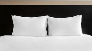 Una cama con ropa blanca y dos almohadas.