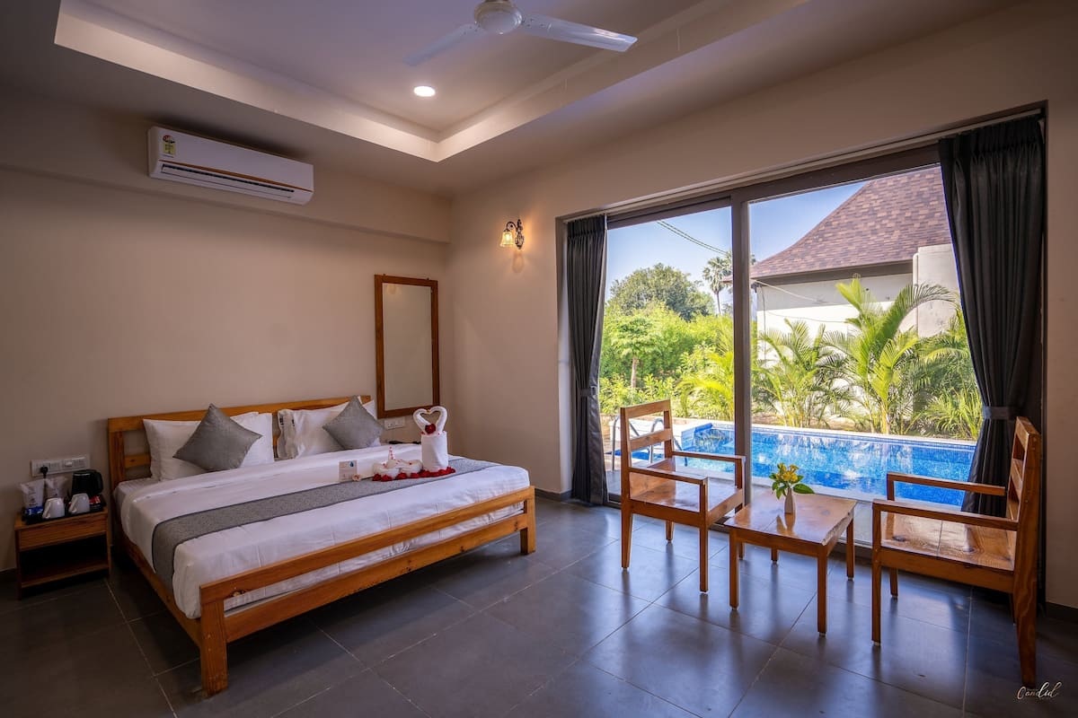 A hotel room with a bed, bedside table, and a view of a swimming pool.