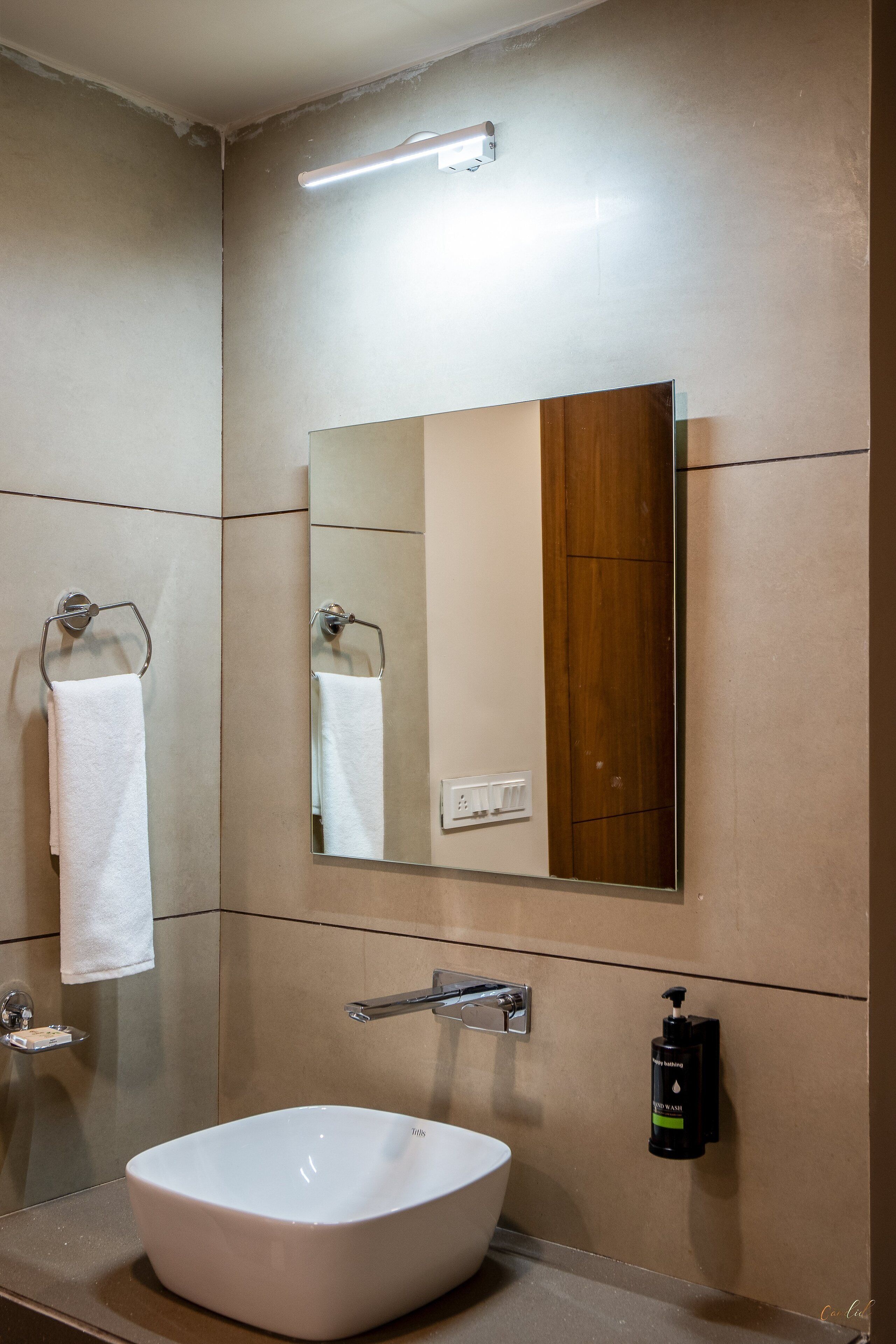 Un bagno con un lavandino bianco, uno specchio e un portascopevoli.