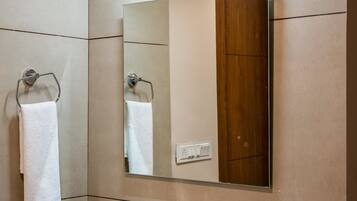 Un bagno con un lavandino bianco, uno specchio e un portascopevoli.