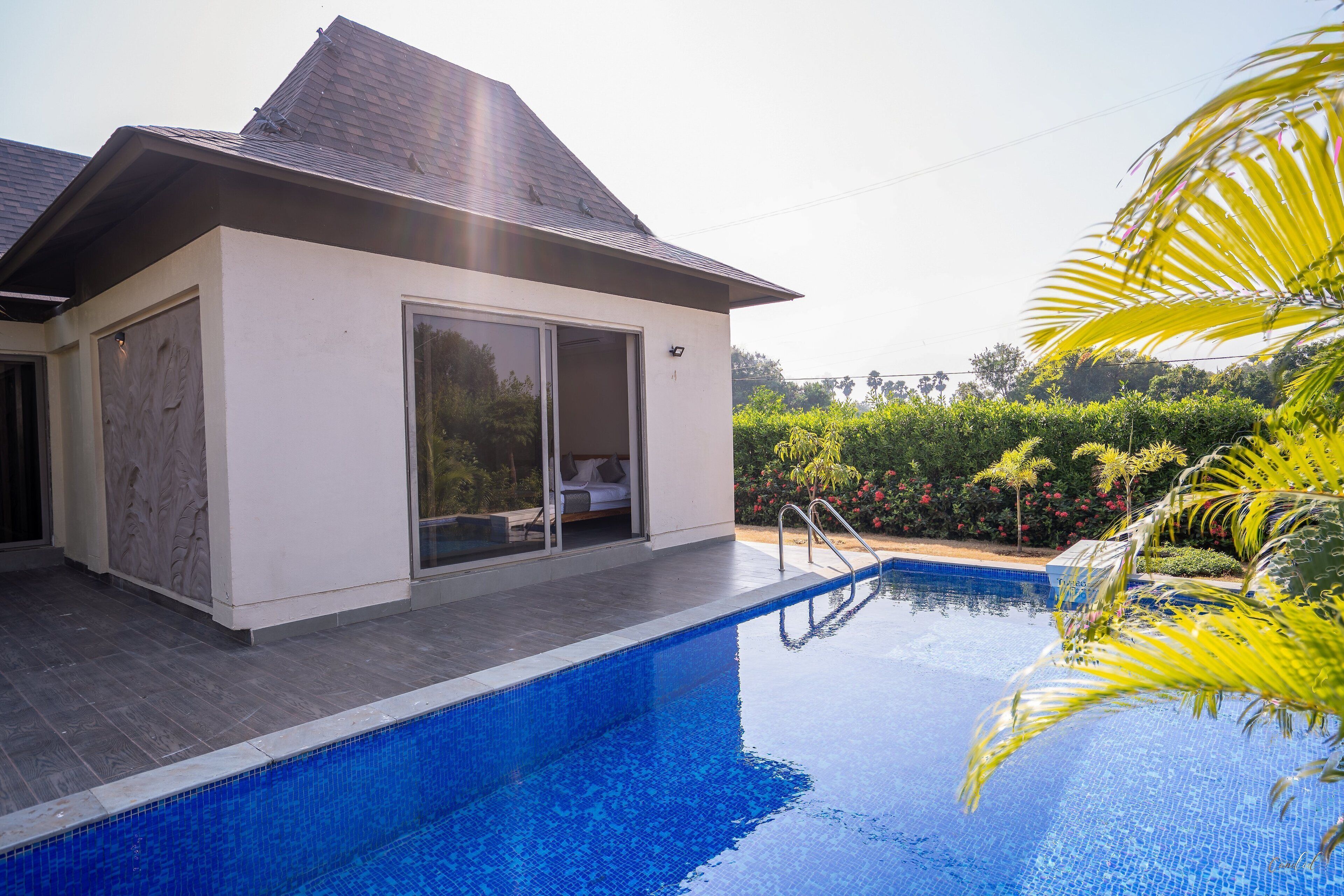 A modern house with a swimming pool, large sliding glass doors, and a well-maintained garden.