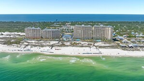 A coastal resort with three high-rise buildings, a sandy beach, and a clear view of the ocean.