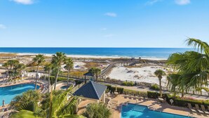 A resort with a pool, beach access, and palm trees.