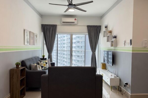 A living room with a sofa, a TV, a ceiling fan, and a window with curtains. - Razak City Residences A3 by Favspace (Kuala Lumpur)
