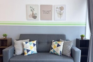 A grey sofa with patterned cushions, a green stripe on the wall, and framed botanical prints. - Razak City Residences A3 by Favspace (Kuala Lumpur)