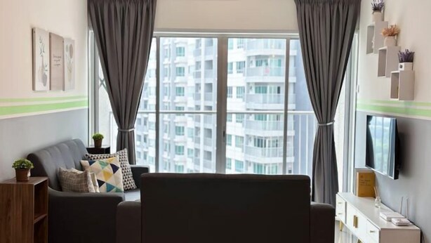 A modern living room with a grey sofa, a TV on the wall, and a large window with curtains. - Razak City Residences A3 by Favspace (Kuala Lumpur)