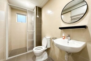 A bathroom with a toilet, sink, mirror, and shower enclosure. - Razak City Residences A3 by Favspace (Kuala Lumpur)