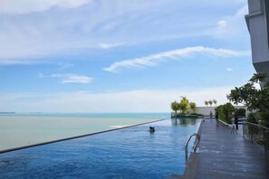 Une piscine avec vue sur la mer, une terrasse en bois et un ciel dégagé.