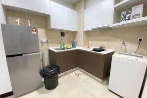 A compact kitchen with a refrigerator, sink, and a small washing machine.
