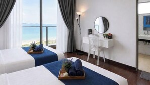 A hotel room with two beds, a desk, a chair, a mirror, and a view of the sea. - Bella Vista Silverscape Seaview Homestay (Melaka)