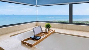 A room with a large window, a laptop on a tray, and a potted plant. - Bella Vista Silverscape Seaview Homestay (Melaka)