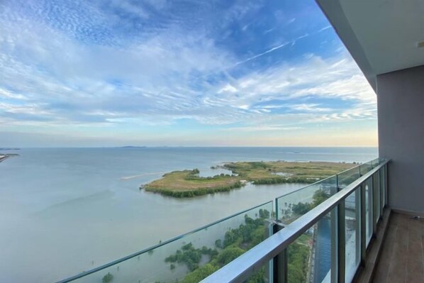 A balcony with a view of a calm body of water and distant land.