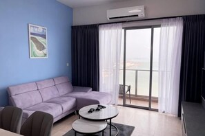Una sala de estar con un sofá, una mesa redonda y vistas a través de un ventanal.