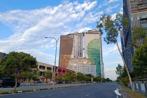 Un immeuble à étages doté d’une architecture moderne, caractérisé par une façade en verre imposante et un élément circulaire verdoyant.