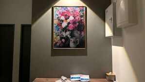 A framed floral painting on a wall, a table with books and a tissue box, and a wall-mounted air conditioning unit. - Entire Unit & 2BR Near Legoland (Iskandar Puteri)