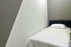 A single bed with a dark headboard in a room with plain walls. - Entire Unit & 2BR Near Legoland (Iskandar Puteri)
