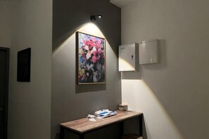 A hallway with a framed floral artwork, a wooden bench, and a wall-mounted light fixture. - Entire Unit & 2BR Near Legoland (Iskandar Puteri)