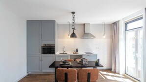 A modern kitchen with grey cabinets, a black countertop, and a dining area with a table and chairs.