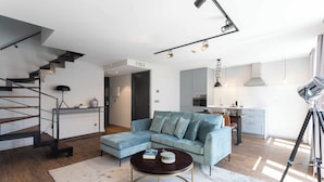 A modern living room with a light blue sofa, a dark coffee table, and a staircase with metal railings.