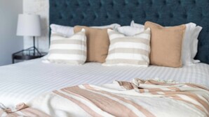 A neatly made bed with striped bedding and multiple pillows.