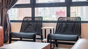 A modern room with two black mesh chairs, a small table, and a large window offering a city view. - The Pano by Minsu (Kuala Lumpur)