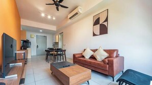 A modern living room with a sofa, coffee table, TV, and a dining area in the background. - The Pano by Minsu (Kuala Lumpur)
