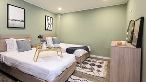 Een moderne slaapkamer met twee bedden, een nachtkastje, een klein kastje en een dienblad met ontbijtartikelen.